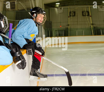 Ein Hockeyspieler auf der Bank in der Eissporthalle ist bereit zu springen, auf dem Eis und Spielen Stockfoto