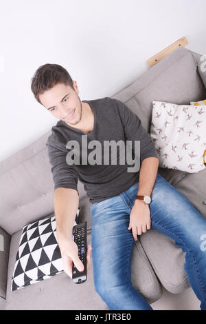 Portrait des jungen Mannes, Fernsehen und entspannt auf der Couch. Im Innenbereich. Stockfoto