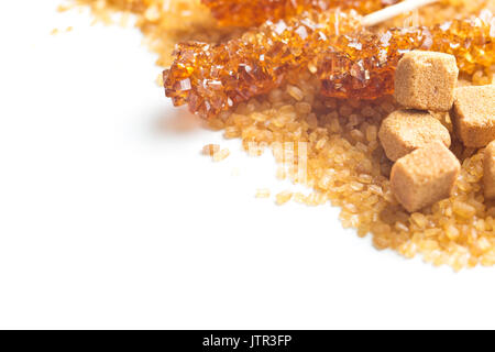 Brauner Rohrzucker, Würfel Zucker und kristallinem Zucker auf Holzstäbchen auf weißem Hintergrund. Stockfoto