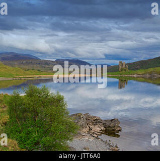 Atemberaubende Landschaft der Highlands mit Loch Assynt mit Ruinen von Ardvreck Castle in Spiegelfläche von Wasser unter stürmischen Himmel in Schottland wider Stockfoto