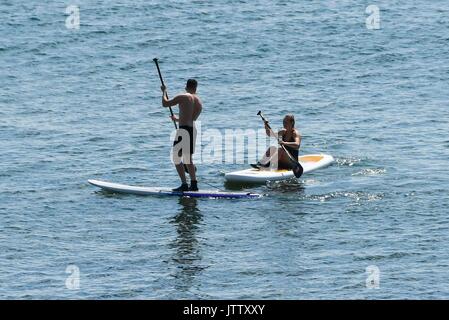 Lyme Regis, Dorset, Großbritannien. 10. August 2017. UK Wetter. Paddel Boarder geniessen die herrliche Sonne auf dem Wasser in den Badeort Lyme Regis in Dorset. Photo Credit: Graham Jagd-/Alamy leben Nachrichten Stockfoto
