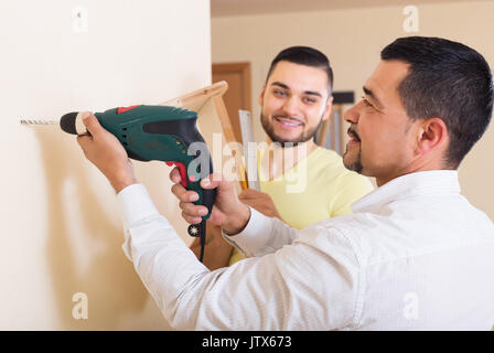 Jungen Sohn und Vater bohren an der Wand im Innenbereich Stockfoto