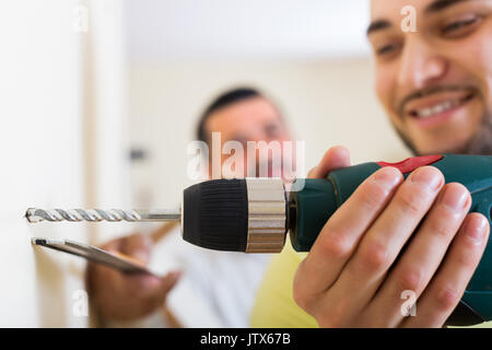 Junge glücklich Sohn und Vater bohren an der Wand im Innenbereich Stockfoto