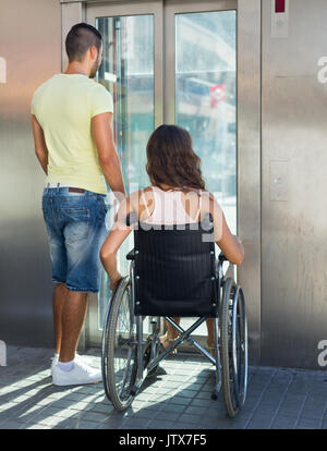 Schöner Mann helfen behinderten Freundin im Freien Fahrstuhl Stockfoto