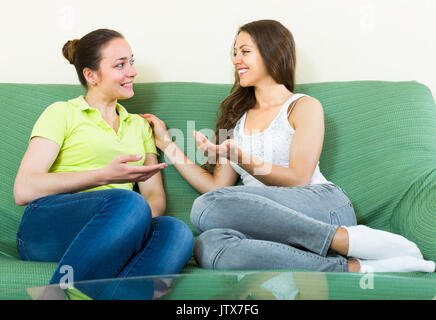 Zwei glücklich lächelnde junge Frauen klatschen auf dem Sofa zu Hause Stockfoto