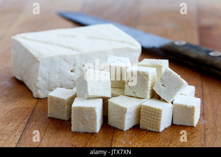 Einzelnen Block von weißen Tofu mit geschnittenen Tofu würfeln und rustikalen Messer auf Holz Schneidebrett. Stockfoto
