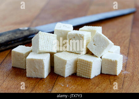 Würfel schneiden weiß Tofu und rustikalen Messer auf Holz Schneidebrett. Stockfoto
