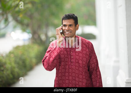Gerne Inder mit einem Smart Phone auf der Straße. Traditionelle indische Männer tragen eine kurta mit Smart Phone außerhalb. Stockfoto