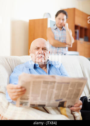 Reifer mann lesen Zeitung gegen die traurige Frau in Home Stockfoto