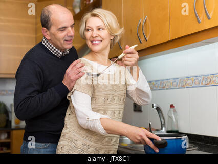 Lächelnd glücklich senior Ehegatten Vorbereitung Mahlzeit zusammen an moderne Küche Stockfoto