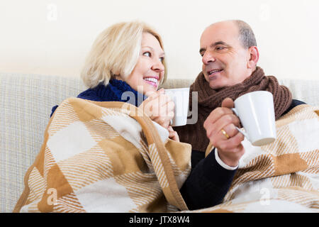 Gerne älteres Paar in Wollschal mit heißem Tee aufwärmen Stockfoto