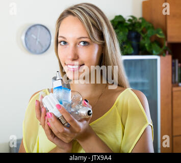 Junge lächelnde Hausfrau holding Glühbirnen zu Hause Stockfoto