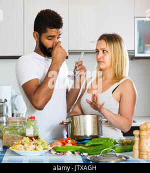 Porträt der jungen interracial Paare mit stinkenden Essen in der Küche zu Hause Stockfoto