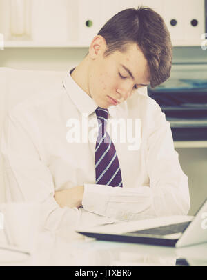 Porträt des jungen Assistenten schlafen im Büro in der Nähe der Dokumente Stockfoto