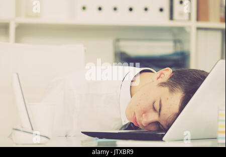 Porträt des jungen Assistenten schlafen im Büro in der Nähe der Dokumente Stockfoto