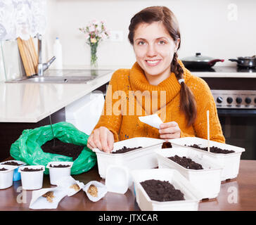 Frau Aussaat Samen im Boden bei Tisch zu Hause Stockfoto
