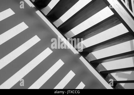 Shadow Streifen Licht auf weißem Beton Wand der thailändischen traditionellen Stil hölzerne Treppe im Morgenlicht. Schwarze und weiße Mehrfachbelichtung Beleuchtung Stockfoto