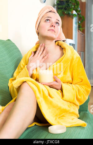 Positive Frau im Bademantel, kosmetische Behandlung auf Gesicht Stockfoto