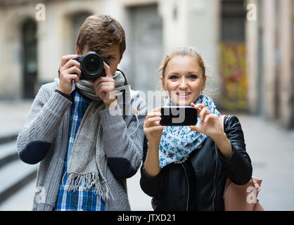 Paar lächelnde junge Reisende, Fotos mit der Digitalkamera und Handy Stockfoto