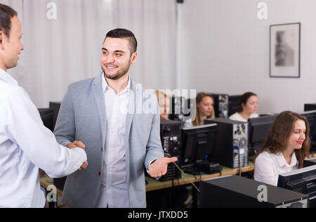 Positive Customer Service Manager zitternden Hand von lächelnden Mitarbeiter im Büro Stockfoto