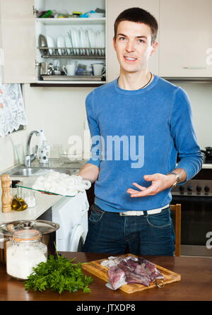 Glückliche Menschen Kochen rohen Tintenfisch in Küche Stockfoto