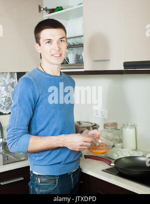 Stattlicher Mann mit Teig und Pfanne in der Küche Stockfoto