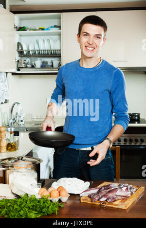 Happy Guy kochen Tintenfischringe in Küche Stockfoto