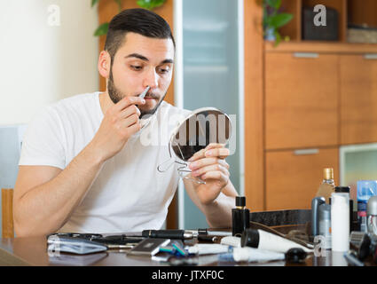 Kerl 20 Jahre alt Haare aus der Nase und Ohren mit Trimmer entfernen Stockfoto