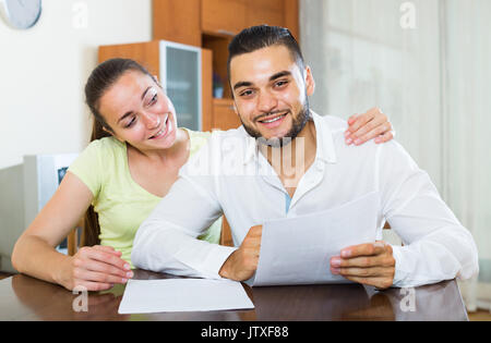 Glückliches amerikanisches Paar diskutieren Vertragsbedingungen zu Hause Stockfoto