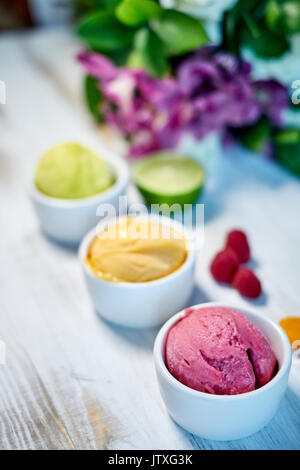 Auswahl an Gourmet Aromen der italienischen Eis in lebendigen Farben in einzelnen Porzellan Tassen auf einem alten rustikalen Holztisch serviert in einer Eisdiele, Betrachtungswinkel und jpg Stockfoto