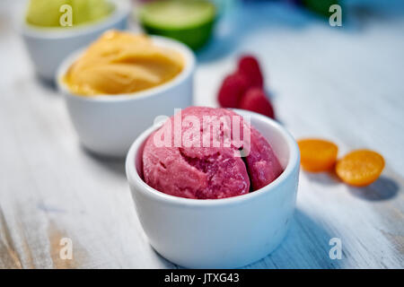 Auswahl an Gourmet Aromen der italienischen Eis in lebendigen Farben in einzelnen Porzellan Tassen auf einem alten rustikalen Holztisch serviert in einer Eisdiele, Betrachtungswinkel und jpg Stockfoto