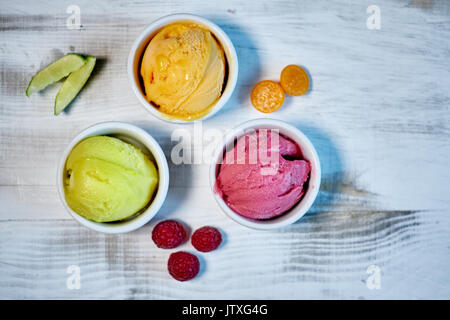 Auswahl an Gourmet Aromen der italienischen Eis in lebendigen Farben in einzelnen Porzellan Tassen auf einem alten rustikalen Holztisch serviert in einer Eisdiele, Betrachtungswinkel und jpg Stockfoto