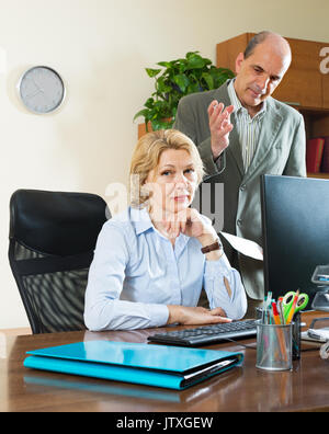Angry Chef bei seiner reife weibliche Assistant schreien Stockfoto