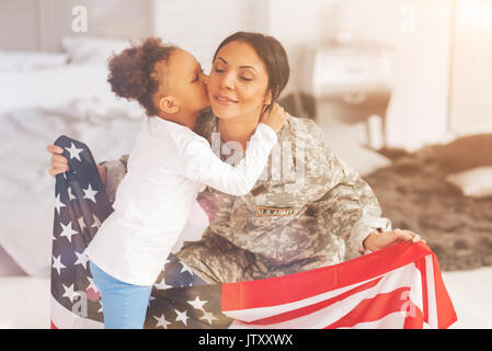 Kleine Tochter küsste ihre Mutter uns Holding flag Stockfoto