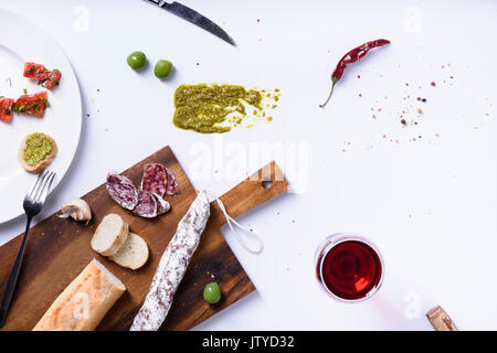 Salami, Oliven und Baguette. Traditionelle spanische fuet Snack. Oben sehen, weißen Hintergrund. Stockfoto