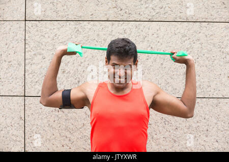 Porträt eines athletischen Inder mit Stretch bands draußen in der urbanen Umgebung. Stockfoto