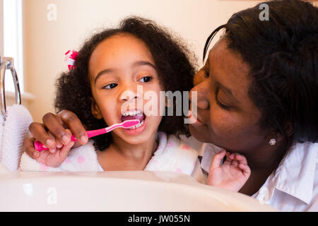 Eine Mutter hilft, ihre junge Tochter putzen ihre Zähne. Stockfoto