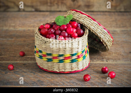 Korb mit Preiselbeeren auf einem hölzernen Hintergrund alte Stockfoto