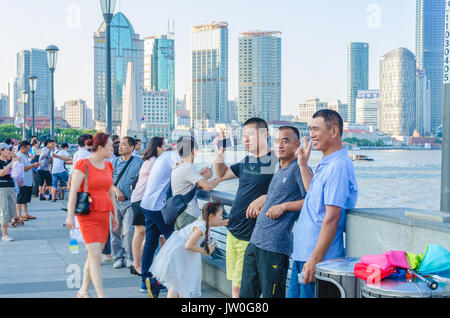 Eine Gruppe von asiatischen Touristen posieren für ein Foto am Ufer des Huangpu River in Shanghai, China. Stockfoto