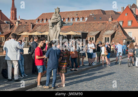 Ein beliebter Zeitvertreib in der deutschen Stadt Würzburg ist ein Treffen mit Freunden bei einem Glas (oder auch zwei) Der fränkischen Wein auf der alten Brücke. Stockfoto