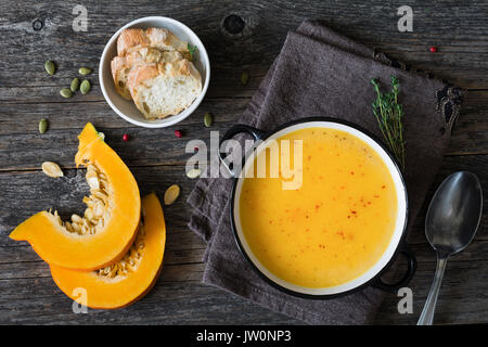 Kürbis creme Suppe in der Schüssel auf rustikalen Holztisch. Ansicht von oben, kopieren Platz für Text Stockfoto