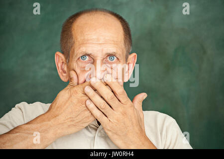 Senior gentleman hält seine Hand auf seinen Mund, und wenn man die Kamera Schockiert Stockfoto