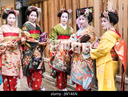 Fünf Geisha in atemberaubenden Kimonos, posieren für Fotos, in einem traditionellen Kyoto street in Japan Stockfoto