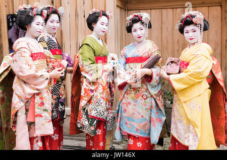 Fünf Geisha in atemberaubenden Kimonos, posieren für Fotos, in einem traditionellen Kyoto street in Japan Stockfoto