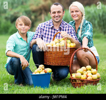 Fröhliche junge Familie mit Körben voller Äpfel in der Landschaft posieren Stockfoto