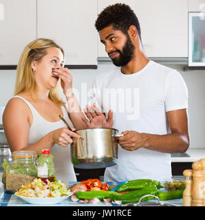 Portrait von interracial junges Paar mit stinkenden Essen in der Küche zu Hause Stockfoto