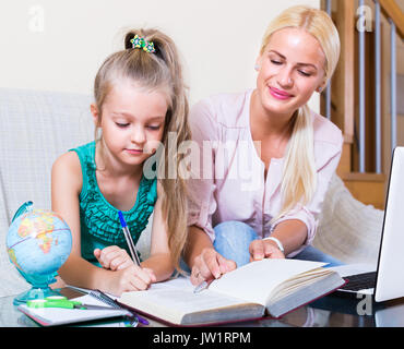 Private junge Lehrer und kleine Mädchen studieren mit Notizen zu Hause Stockfoto