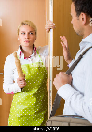 Ernster Konflikt zwischen wütenden jungen Hausfrau und ihr Mann an der Tür Stockfoto