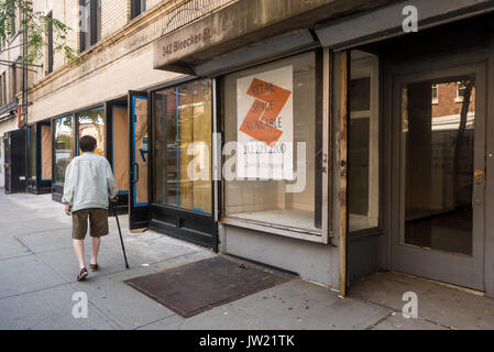 New York, NY, USA - Eine ältere Frau mit einem Stock Wanderungen vorbei an einigen der vielen Leere Läden für Miete auf Bleecker Street, unbesetzt bleibt aufgrund der hohen Mieten. © Stacy Walsh Rosenstock Stockfoto