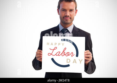 Ernsthafte Geschäftsmann Holding eine weiße Karte gegen digitale zusammengesetzten Bild der glücklichen Tag der Arbeit Text mit blauer Rahmen Stockfoto